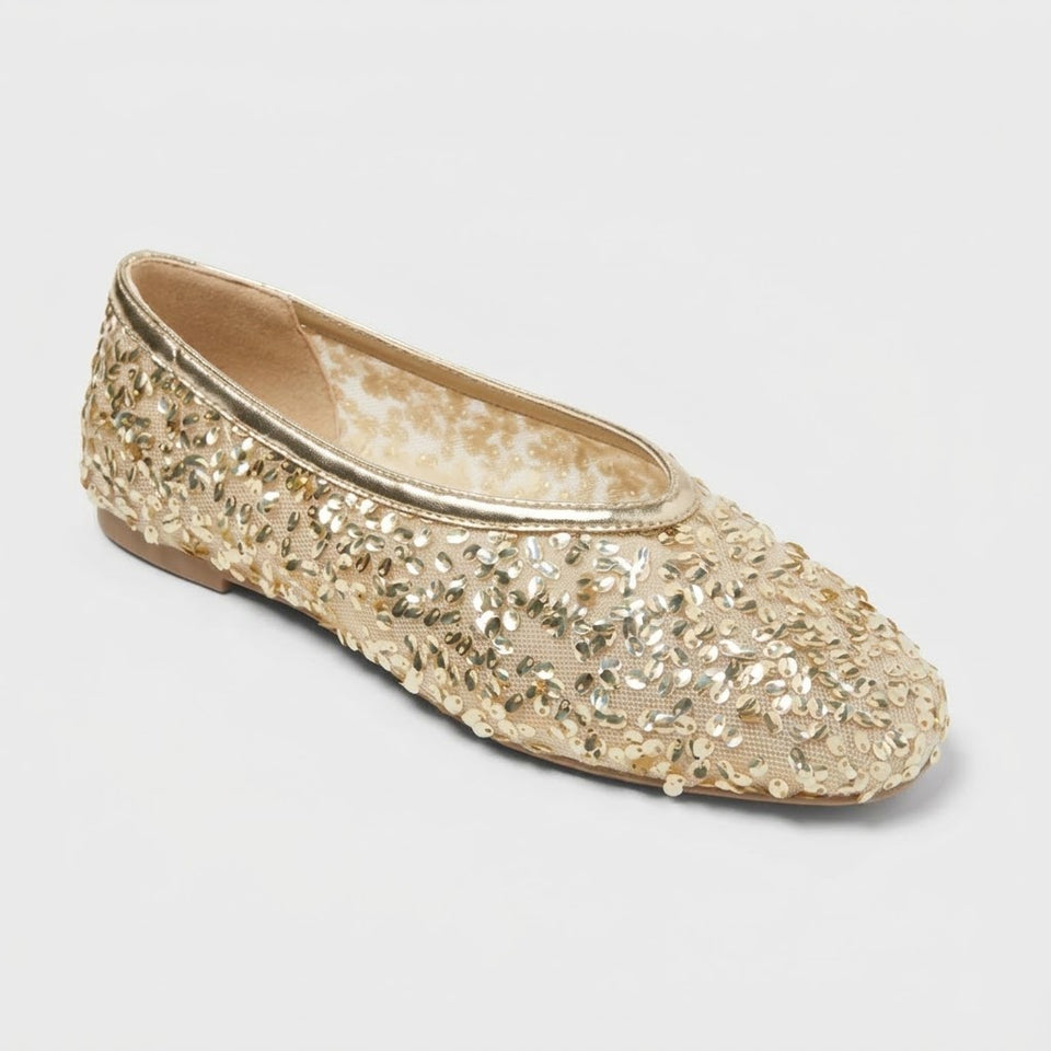 Gold glittery flat shoe on a light gray background