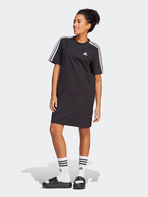 Woman wearing a black Adidas dress with white stripes on a white background