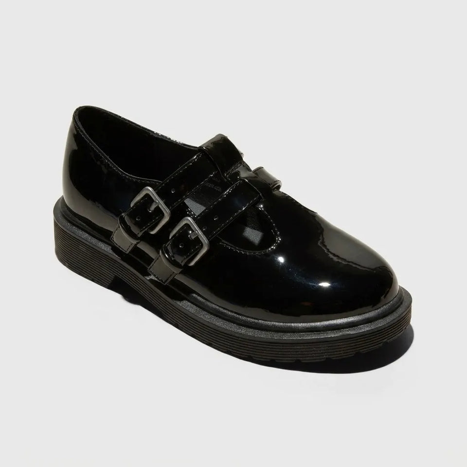 A single black patent leather double-strap shoe with silver-tone buckle details and a chunky black sole, shown on a light gray background.