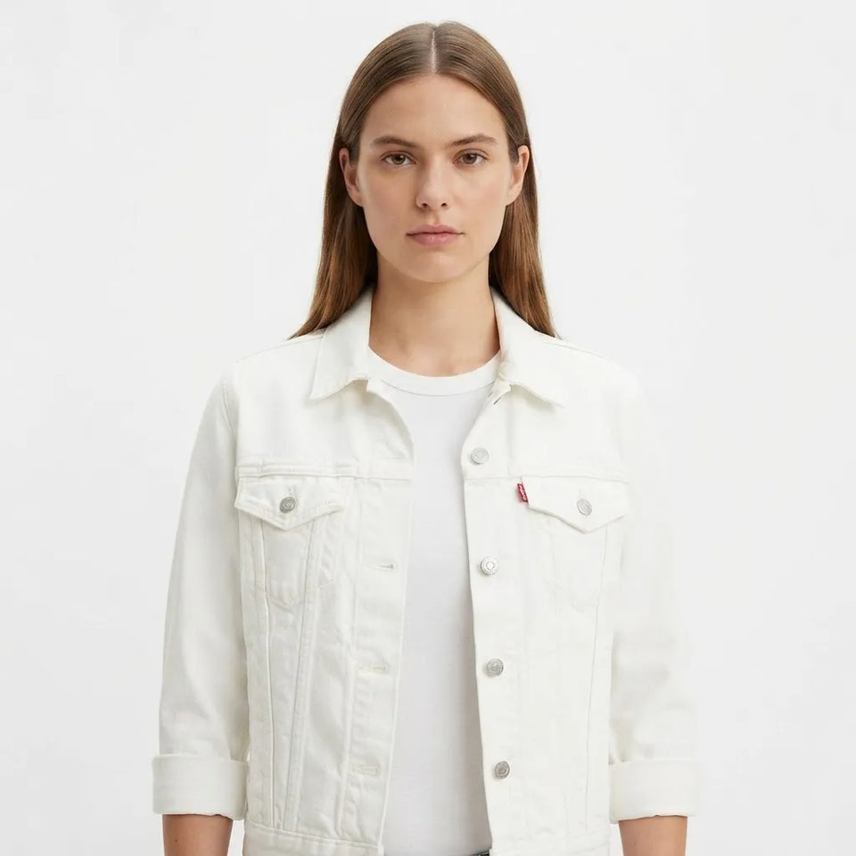 A woman wearing a white denim jacket over a white t-shirt, photographed against a solid white studio background.