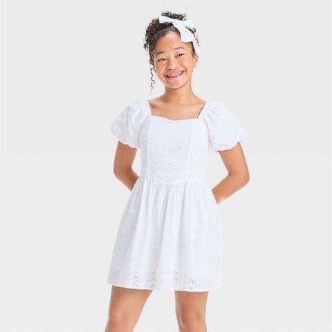 Young girl wearing a white dress with a plain background