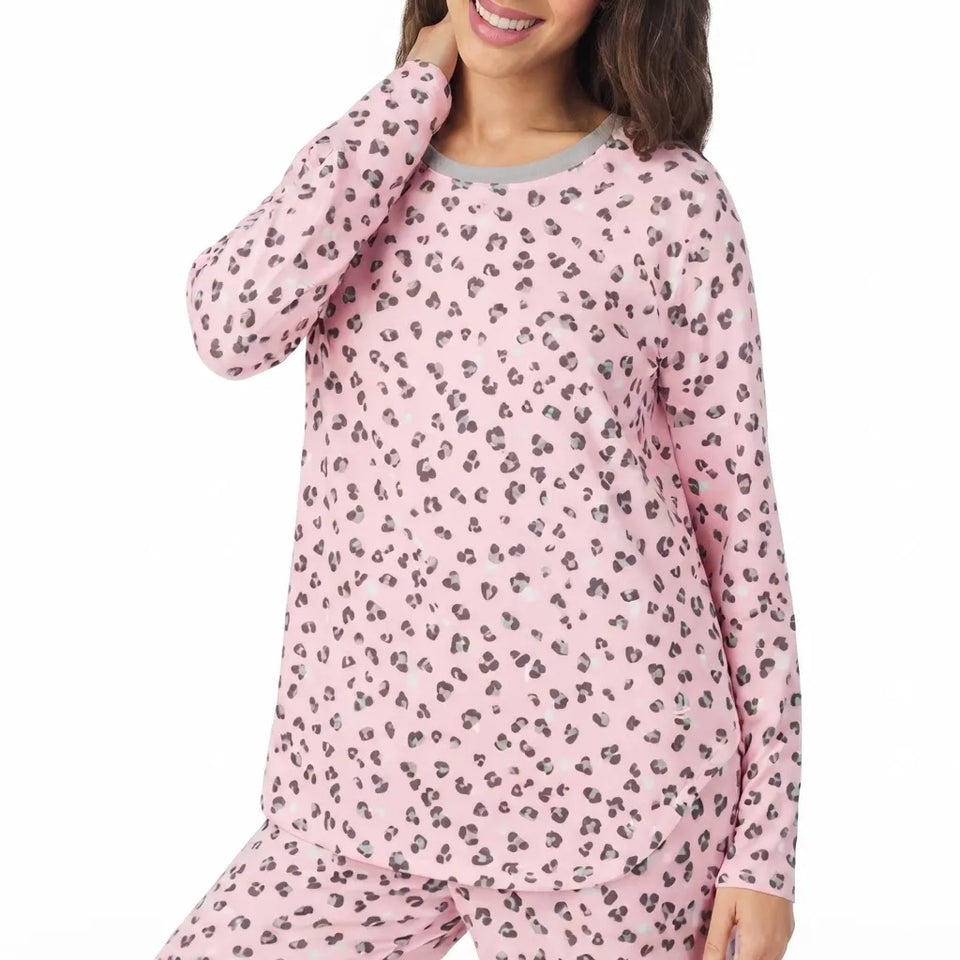 A woman wearing a pink long-sleeve pajama top and matching pants with a gray and black leopard print, shown against a plain white background.