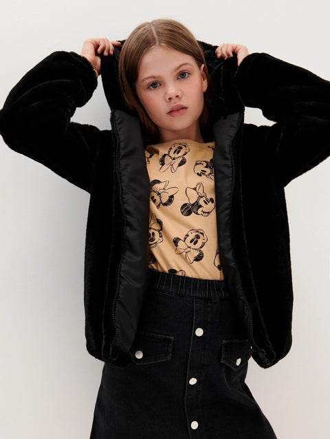 Person wearing a black jacket over a beige shirt with cartoon designs on a white background