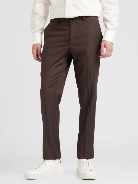 Brown dress pants worn by a person on a white background