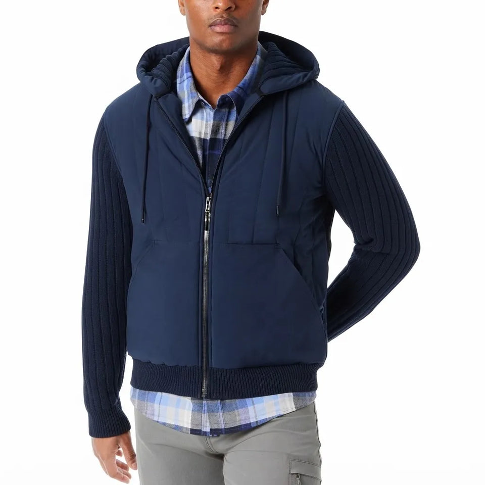 A man wearing a navy blue zip-up hooded jacket with ribbed knit sleeves and a quilted front, layered over a blue and white plaid shirt.