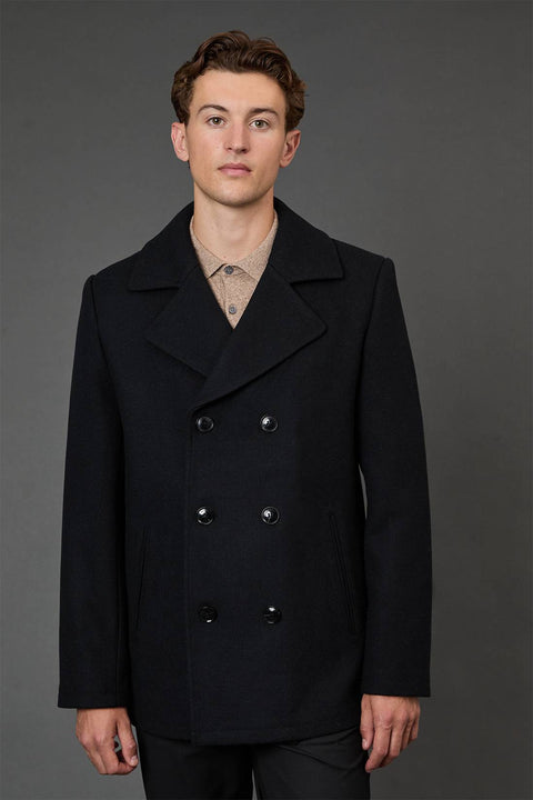 Man wearing a black coat against a gray background