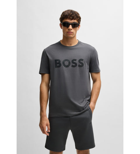 Man wearing a gray 'BOSS' t-shirt and black shorts on a light gray background