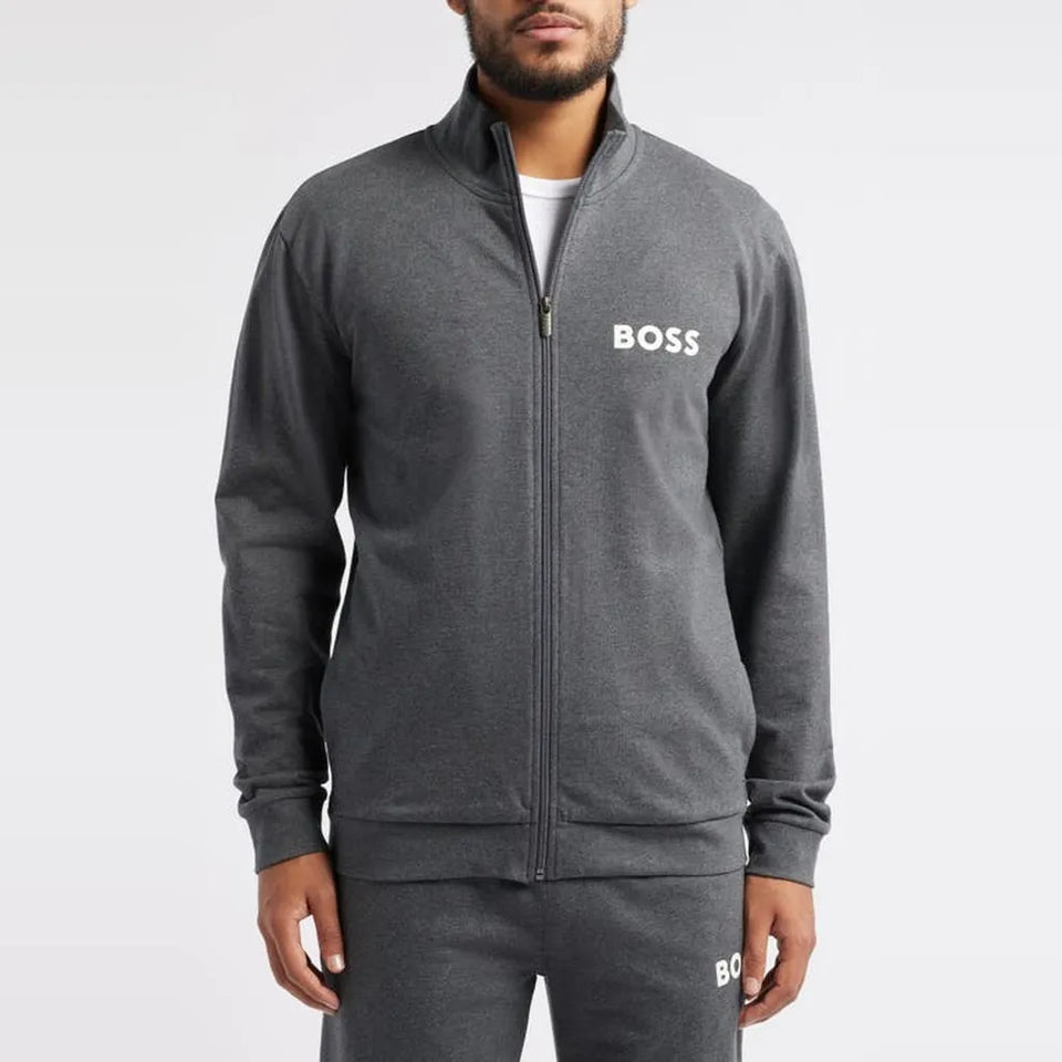 A man wearing a dark gray heather zip-up track jacket with a white BOSS logo on the left chest, paired with matching dark gray sweatpants, shot against a light gray studio background.