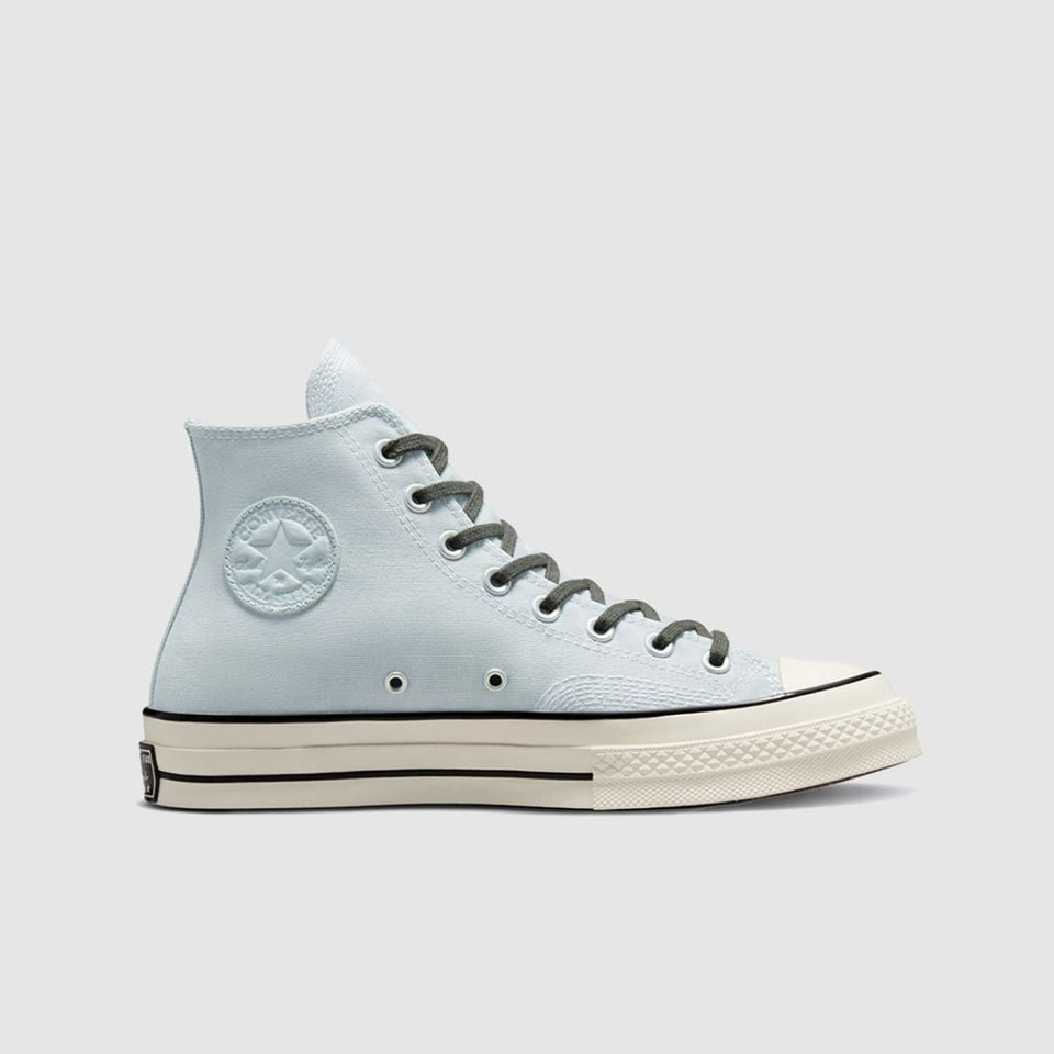 A light blue high-top sneaker with dark gray laces, a white rubber toe cap, and a cream-colored midsole, shown from a side profile on a light gray background.