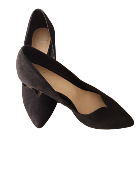 Black pointed-toe shoes on a light wooden surface