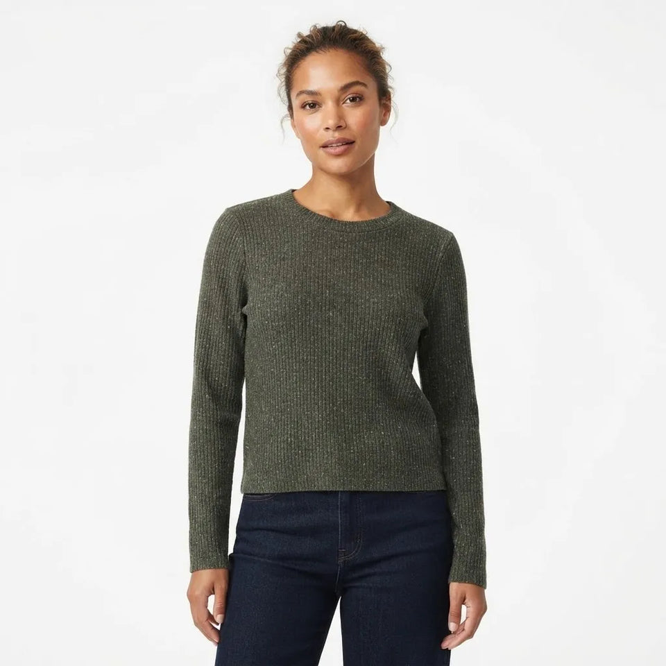 A woman modeling a dark olive green ribbed knit crewneck sweater with dark blue jeans, shot against a plain white studio background.