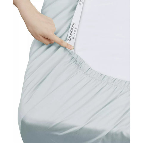 Light blue fitted sheet with a hand holding a white tag displaying 'Genuinerest'.