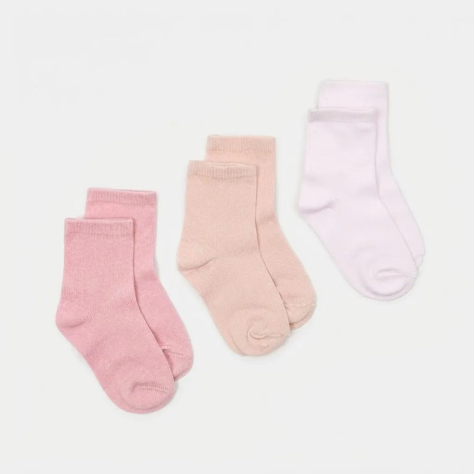 Three pairs of children's crew socks in soft pastel colors, including dusty pink, pale peach, and very light pink, arranged on a clean white background.