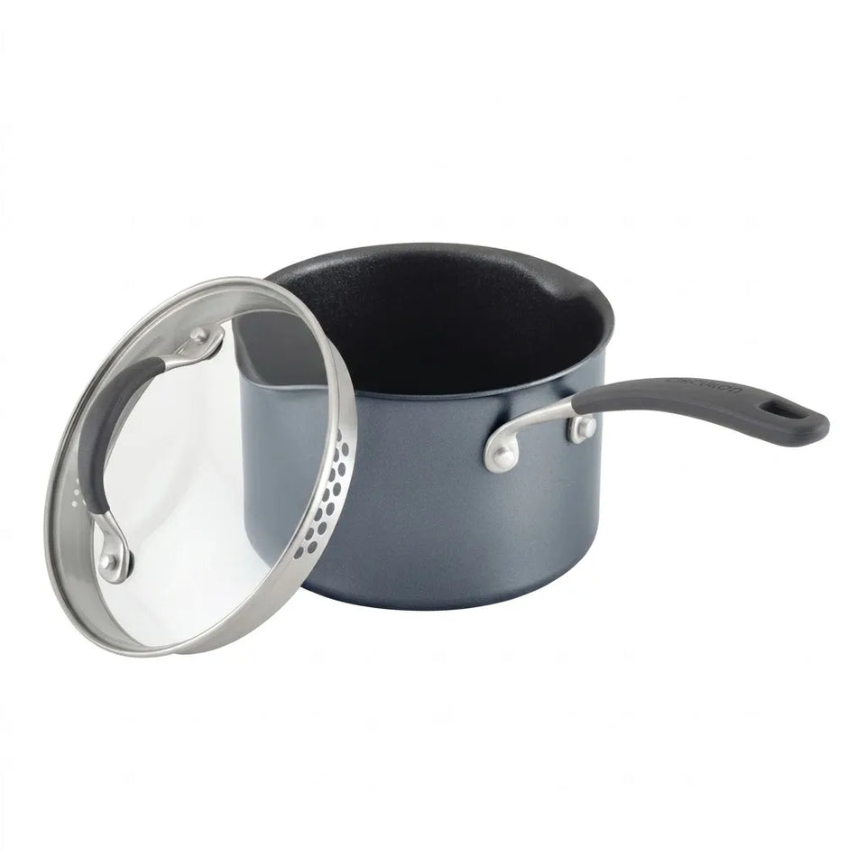 A dark gray non-stick saucepan with a black handle and a clear glass lid with a silver metal rim, shown on a white background.