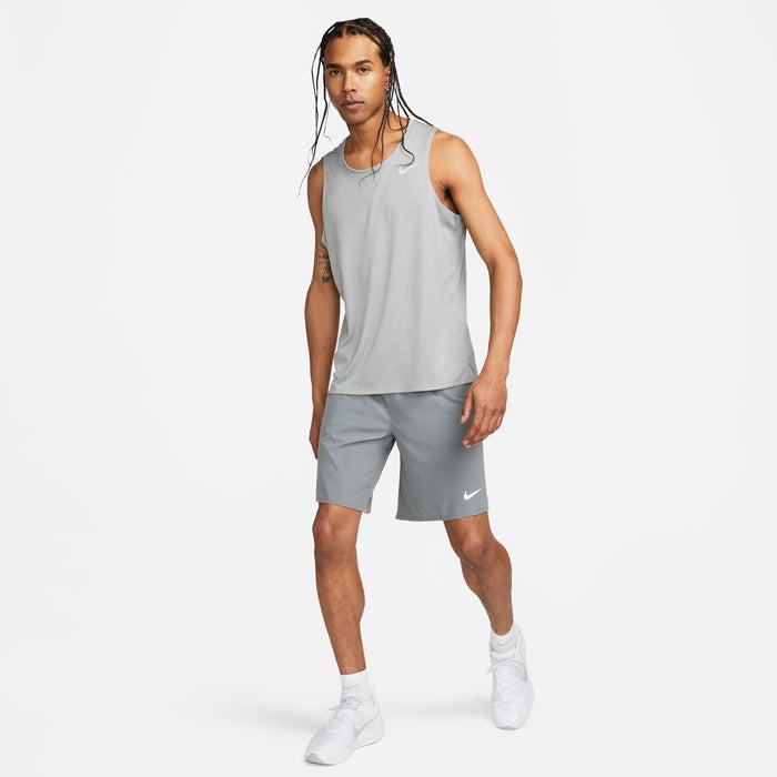 Person wearing a gray Nike tank top and shorts on a white background