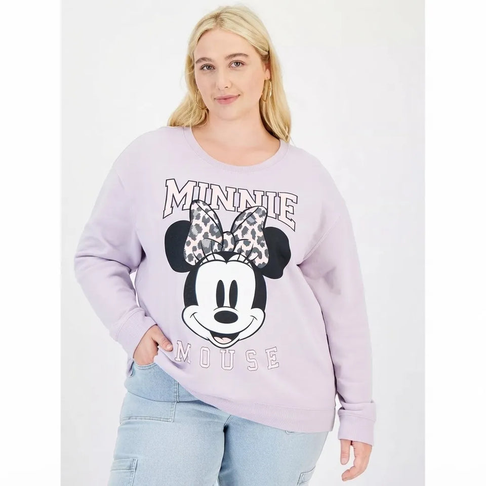 A woman modeling a light purple long-sleeve sweatshirt featuring a large Minnie Mouse graphic on the front, paired with light blue jeans against a plain white studio background.