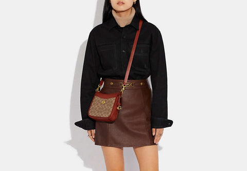 Person wearing a black shirt and brown skirt with a red handbag on a white background
