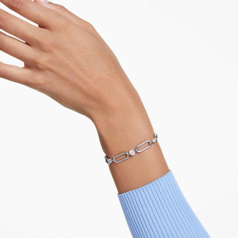 Hand wearing a silver bracelet on a light background