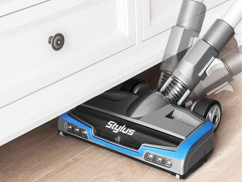 Stylus vacuum cleaner under a piece of furniture on a wooden floor
