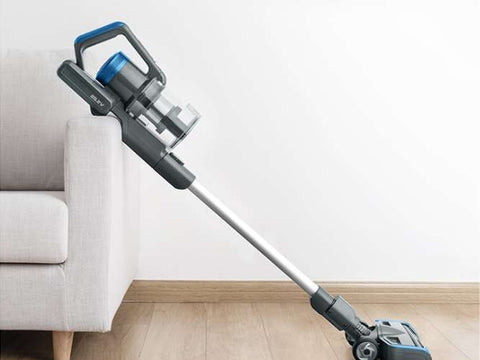 Cordless vacuum cleaner on a wooden floor with a white wall and sofa in the background