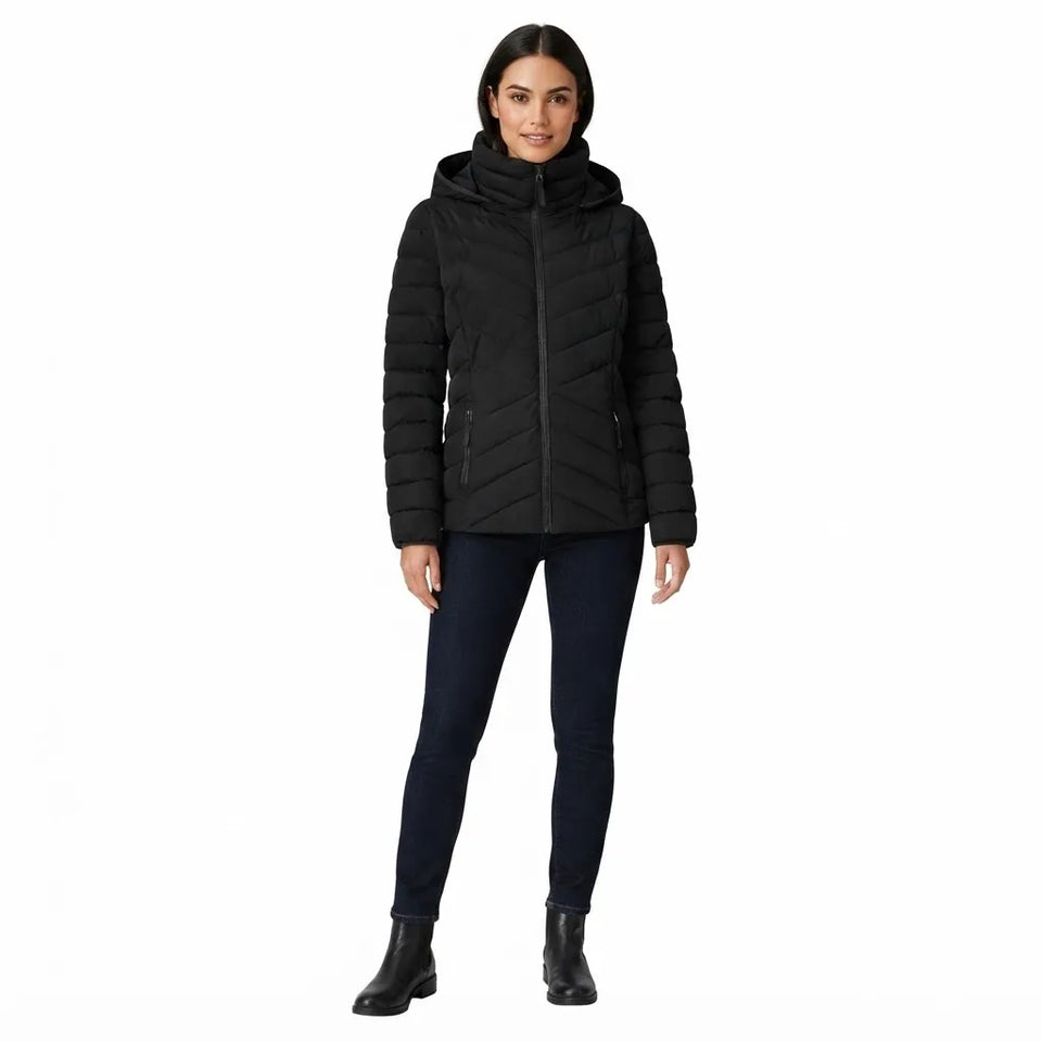 A woman modeling a black hooded puffer jacket with horizontal quilting, paired with dark blue skinny jeans and black ankle boots, against a plain white background.