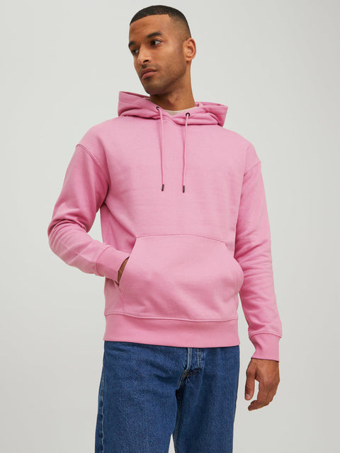 Man wearing a pink hoodie and blue jeans on a light gray background