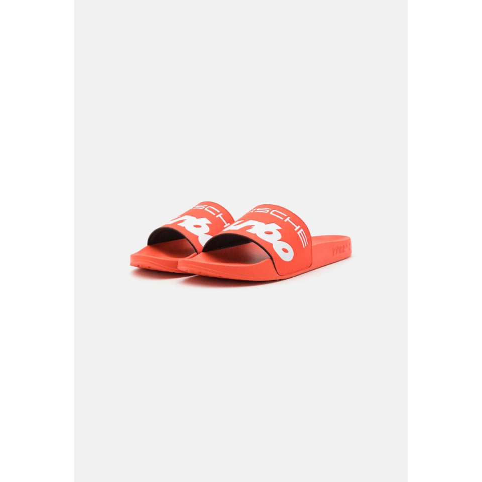A pair of bright orange slide sandals with white Porsche branding on the straps, displayed on a clean light gray background.