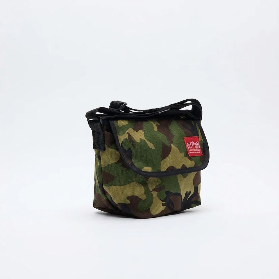 A small camouflage shoulder bag with a black strap and trim, featuring a red rectangular brand patch on the front, set against a plain white background.