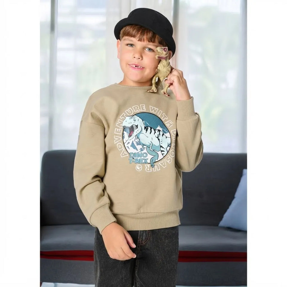 A young boy wearing a beige crewneck sweatshirt with a dinosaur graphic, a black bowler hat, and dark jeans, holding a small dinosaur toy near his face in an indoor setting.