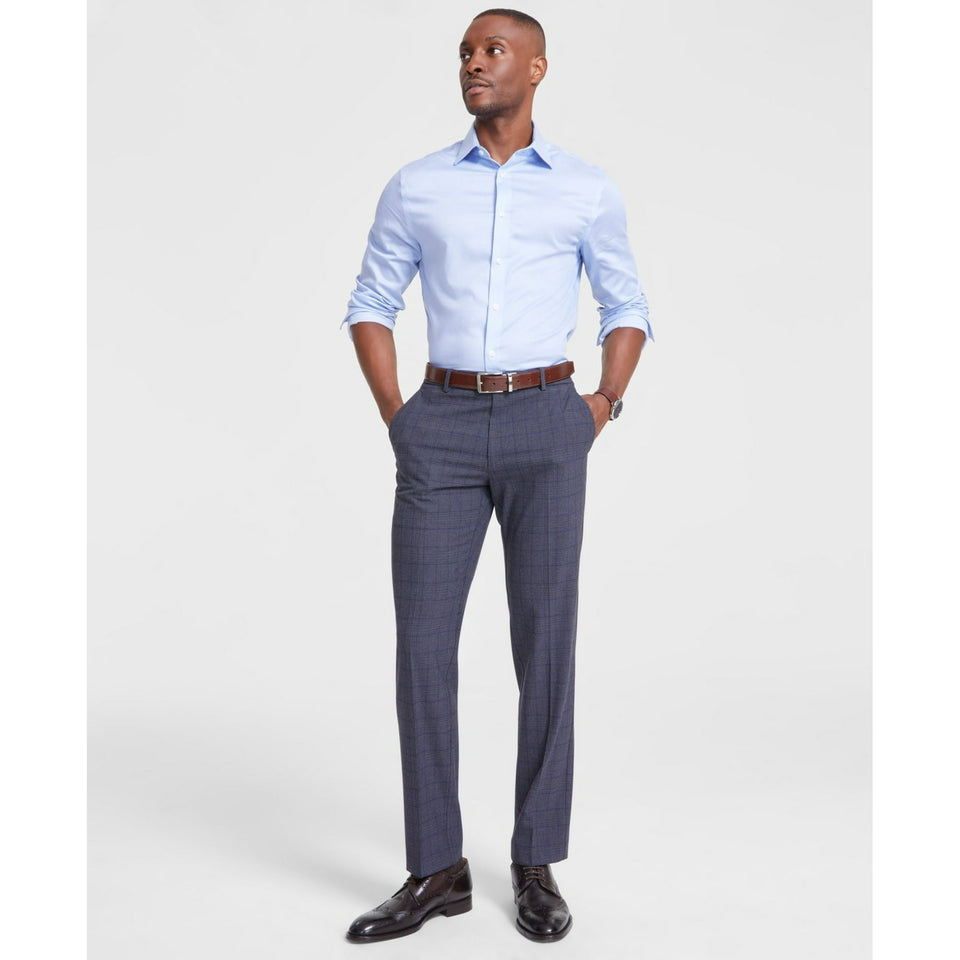 Man wearing a light blue dress shirt and gray checkered pants on a white background