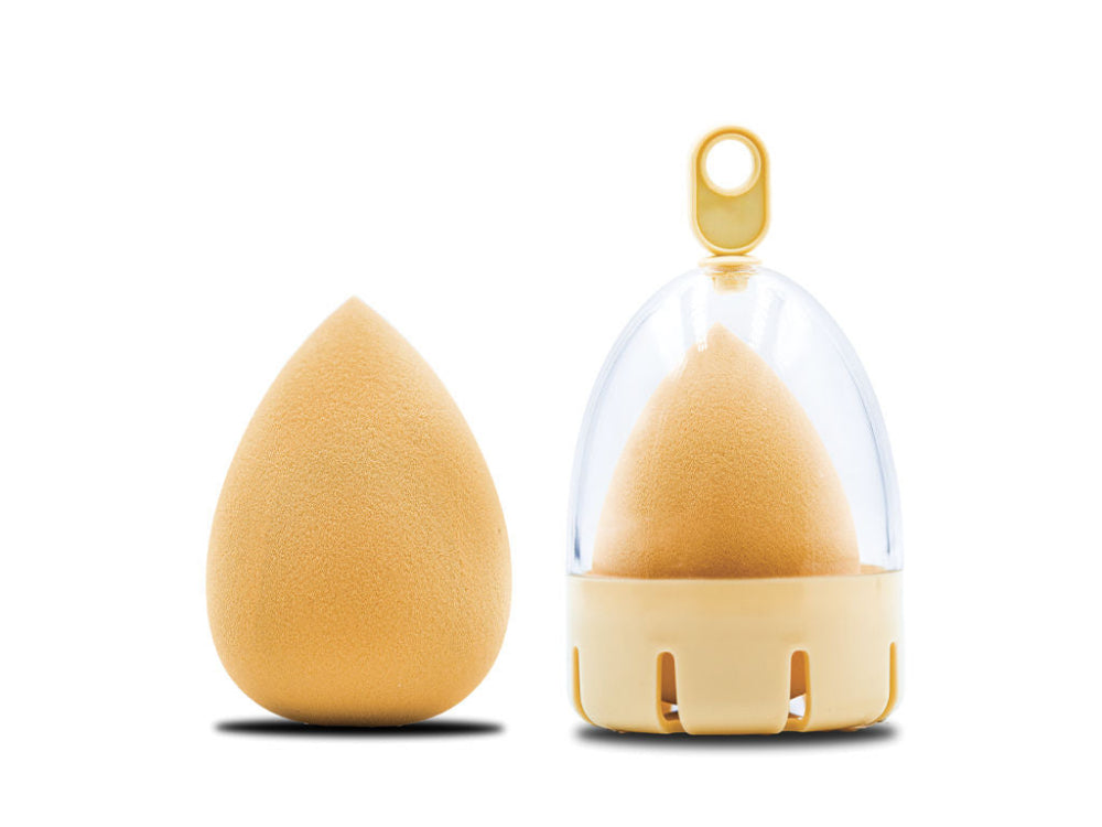 A teardrop-shaped beauty blender sponge alongside its holder, both in a velour texture, displayed against a white background.