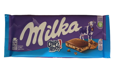 Milka chocolate bar in a blue wrapper held by a hand with a blurred background