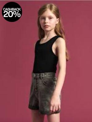 Young girl wearing a black tank top and gray shorts against a pink background