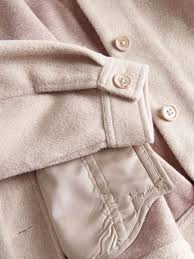Close-up of a beige coat with buttons and leather patch