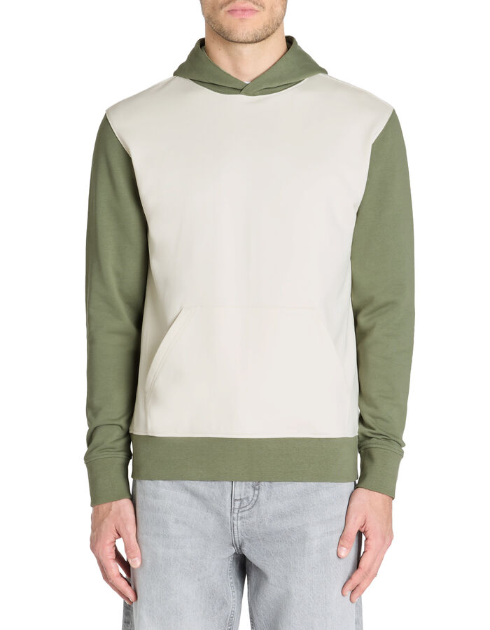 Man wearing a two-tone hoodie with green sleeves and a cream body on a white background