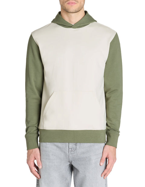 Man wearing a two-tone hoodie with green sleeves and a cream body on a white background