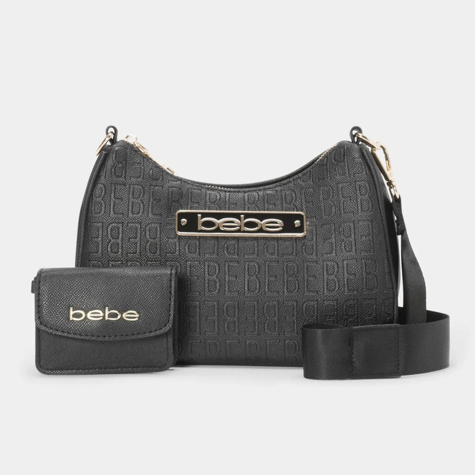 A black embossed crossbody bag with a matching zippered wallet and a detachable shoulder strap, featuring a gold-tone 'bebe' logo plaque on the front, set against a light gray background.