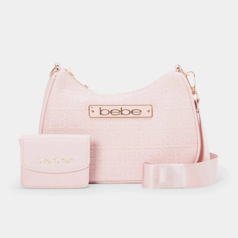 A light pink hobo-shaped shoulder bag with a matching small wallet and a wide matching belt, all featuring a subtle embossed pattern and a gold-tone 'bebe' logo plaque, set against a plain light gray background.