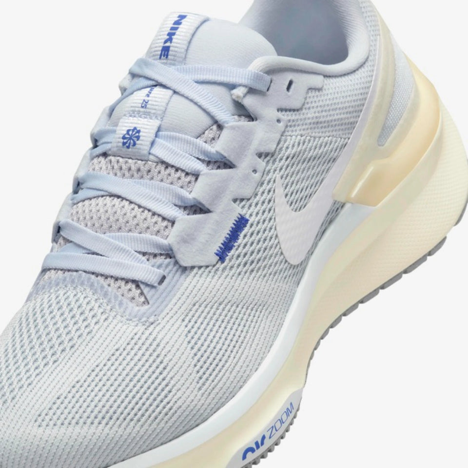 A close-up of a Nike running shoe in light gray and white mesh with blue accents and a beige midsole.