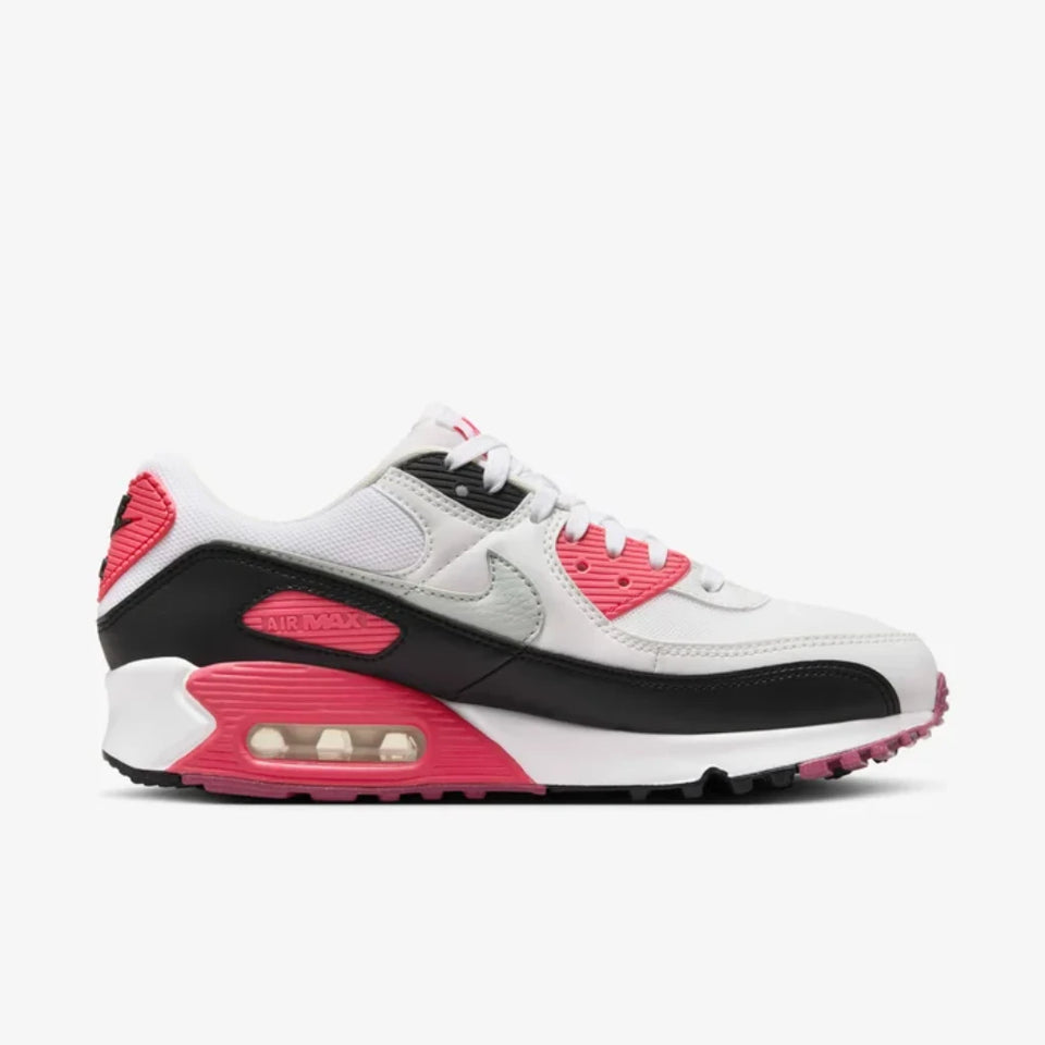 A Nike Air Max 90 sneaker in white, black, and bright pink, shown from a side profile view against a light gray background.