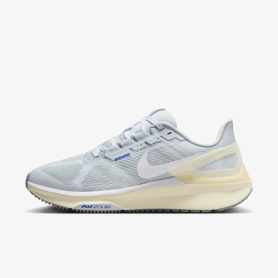 A Nike running shoe in light gray and white mesh with a beige heel counter and a blue 'AIR ZOOM' text detail on the midsole, shown against a light gray background.