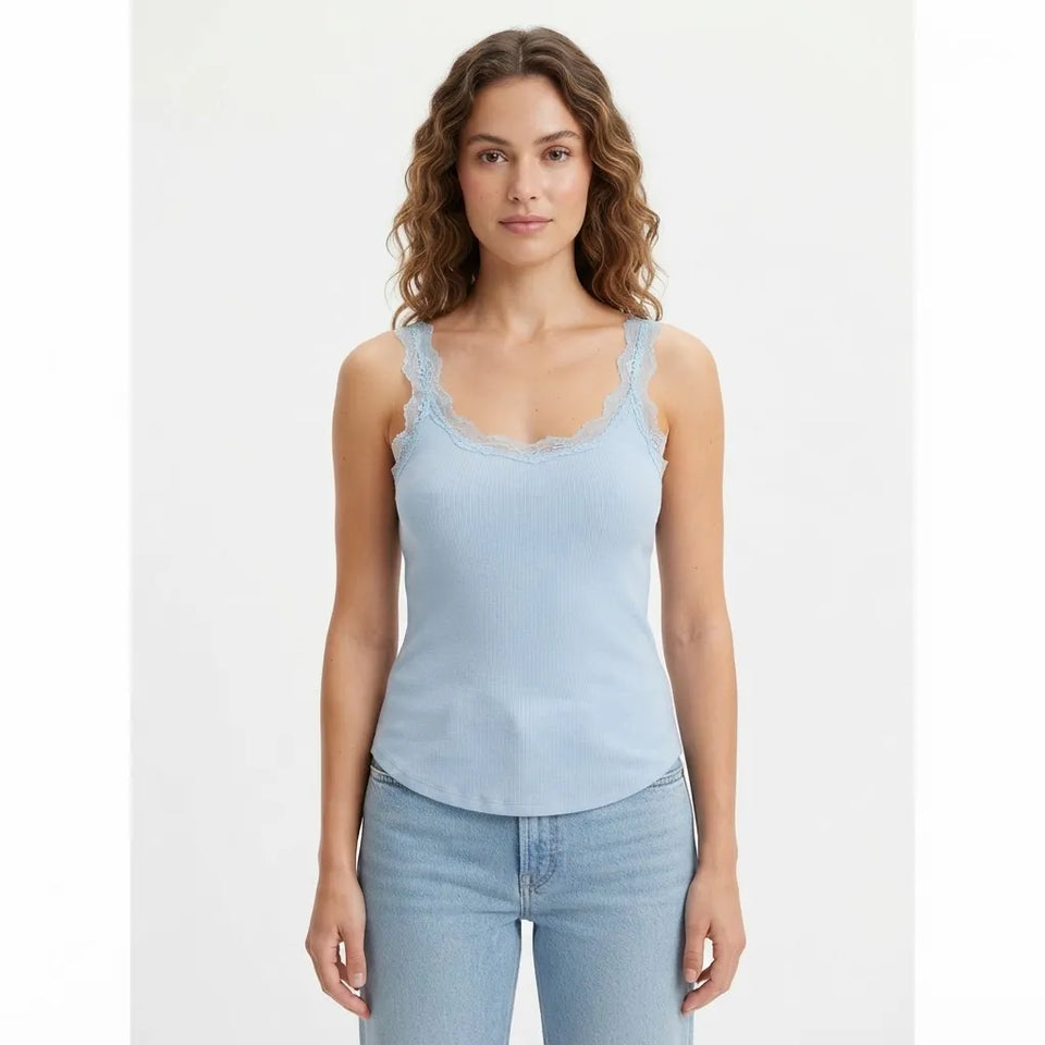 A woman modeling a light blue ribbed tank top with delicate lace trim along the scoop neckline, paired with light-wash blue jeans against a plain white studio background.