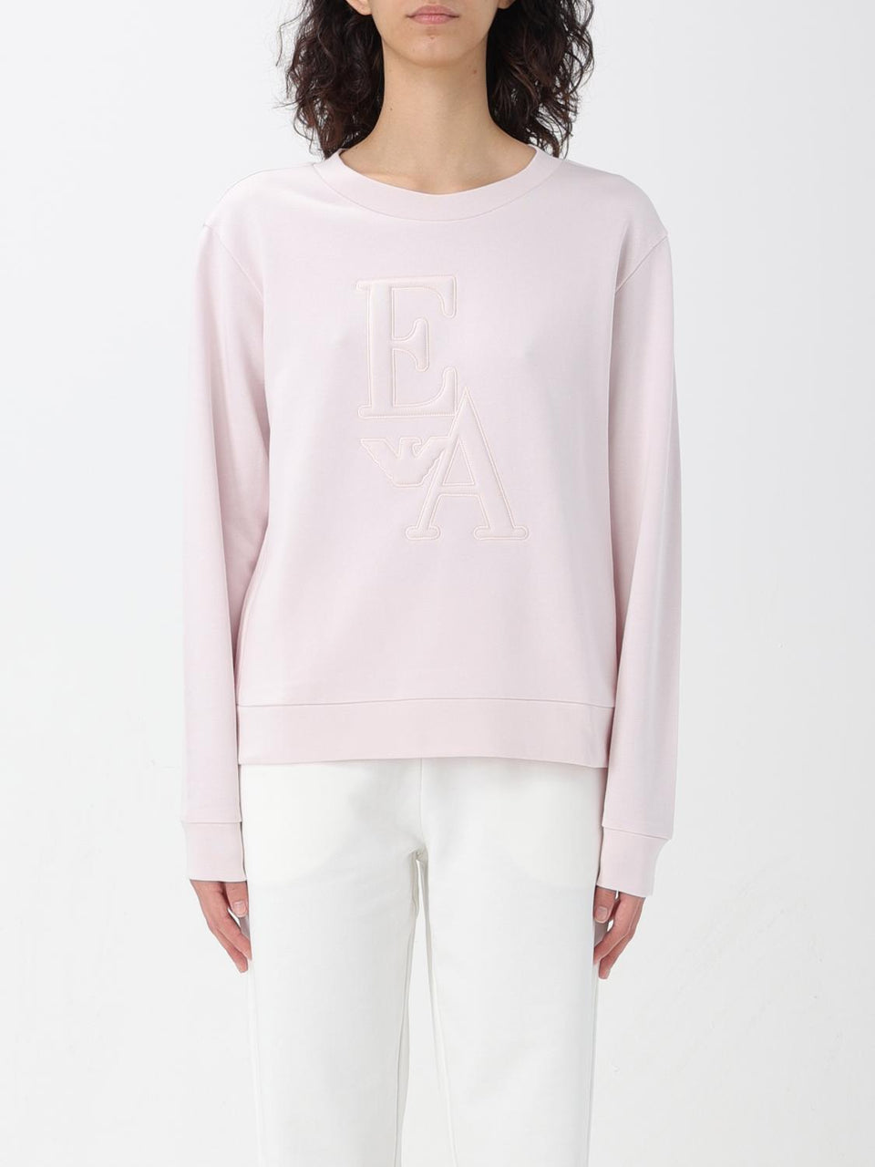 Person wearing a light pink sweatshirt with a logo on a white background