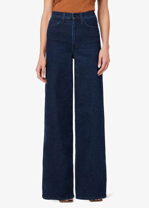 Person wearing dark blue wide-leg jeans on a white background