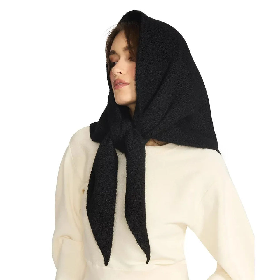 A woman wearing a black knit headscarf or bonnet tied under her chin, paired with a cream-colored top, set against a plain white background.