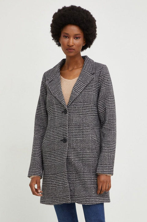 Woman wearing a checkered coat on a plain background