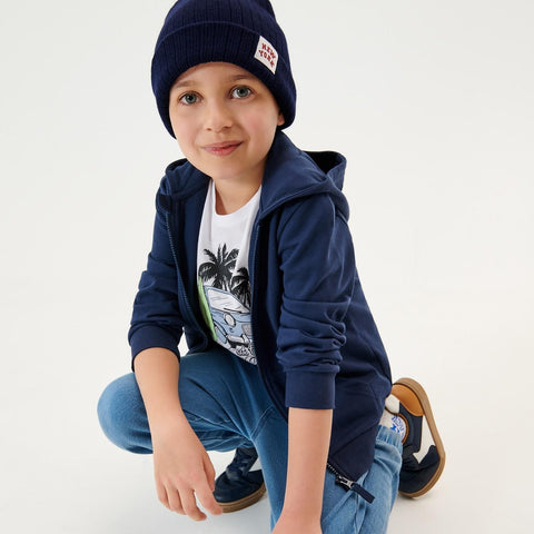 Child wearing a navy blue hoodie, beanie, and jeans on a white background