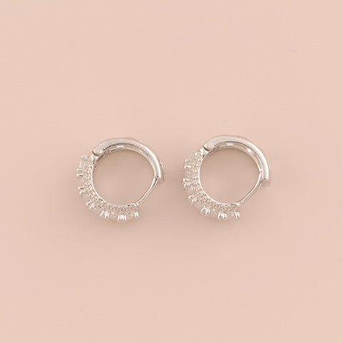 Silver hoop earrings with small stones on a beige background