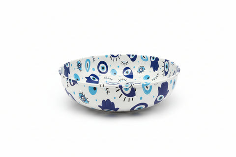 Round blue and white cushion with eye pattern on a desk next to a laptop