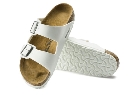 White Birkenstock sandals with brown soles on a white background